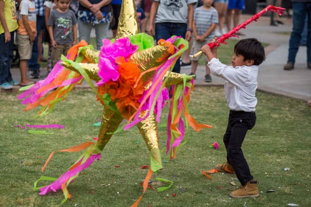 A child beats a pinata full of candy on the plaza during the Cinco De Mayo Fiesta  of Mesilla, New Mexico
