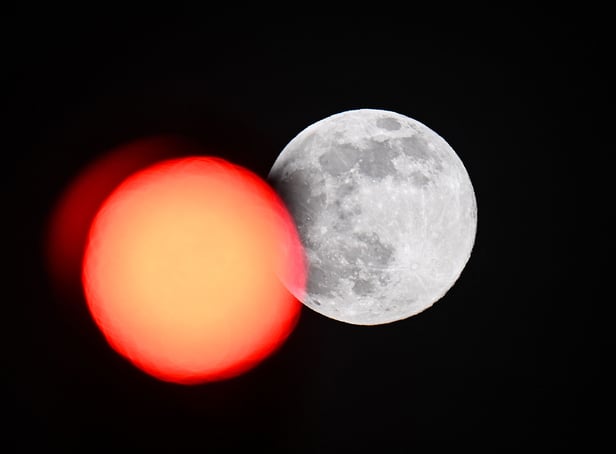 <p>TOPSHOT - This picture taken on February 5, 2023 shows the full moon rising behind a red crossing light in Paris. (Photo by Stefano RELLANDINI / AFP) (Photo by STEFANO RELLANDINI/AFP via Getty Images)</p>