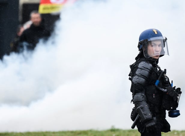 <p>A French gendarme stands next to smoke during a demonstration as part of a national day of strikes and protests, a week after the French government pushed a pensions reform through parliament without a vote, using the article 49.3 of the constitution, in Nantes, western France, on March 23, 2023</p>