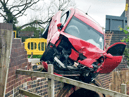 Mangled car left dangling over canal as passenger makes great escape into water 