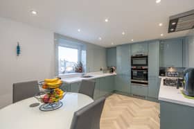 The modern and recently completed kitchen/diner with a range of integrated white goods, glass panelling around worktop area and splash areas and downlights while being finished with stylish gloss units and a fresh white Corian worktop.