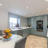 The modern and recently completed kitchen/diner with a range of integrated white goods, glass panelling around worktop area and splash areas and downlights while being finished with stylish gloss units and a fresh white Corian worktop.