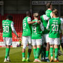 Hanlon is lifted aloft in a scrum of Hibs players celebrating his goal.