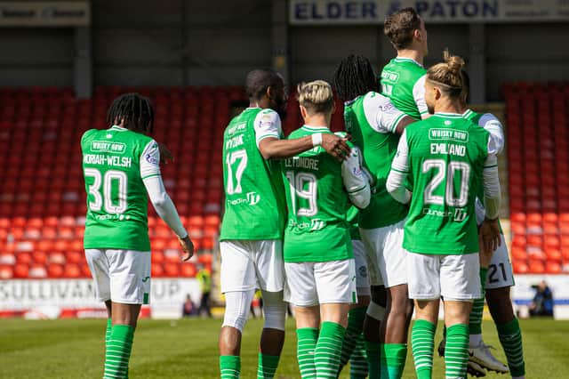 Hanlon is lifted aloft in a scrum of Hibs players celebrating his goal.
