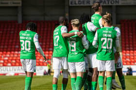 Hanlon is lifted aloft in a scrum of Hibs players celebrating his goal.