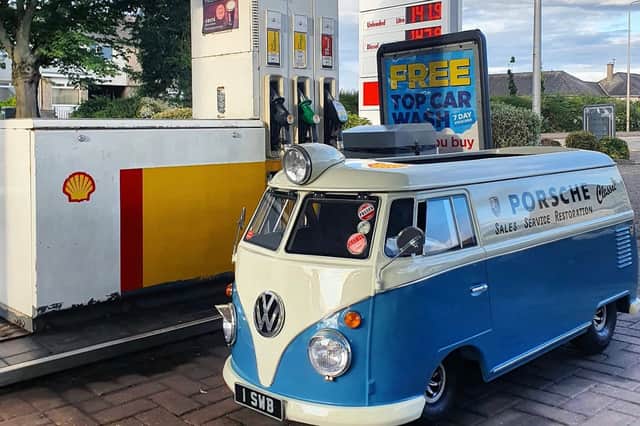 The miniature camper van stops at a petrol station to get some fuel.