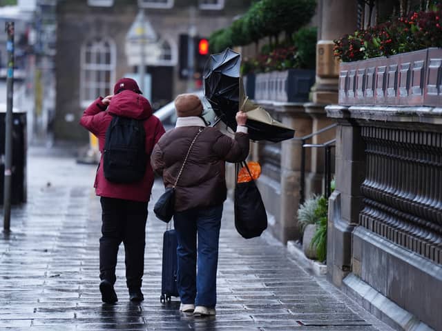 A couple battle with an umbrella in the wind during Storm Eowyn on Princes Street, Edinburgh (Jane Barlow/PA)