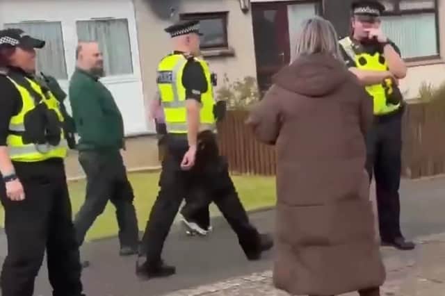A local woman confronts the convicted sex offender as he is led away by police from his home on Saturday.