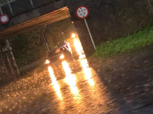 Cars attempting to drive on a flooded road under a bridge in Longniddry. 