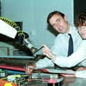 Student Andrew McGlashan is handed a pen by a robotic arm at Napier University, watched by Dr Des Bonnar of the Engineering department, October 1992.