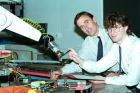 Student Andrew McGlashan is handed a pen by a robotic arm at Napier University, watched by Dr Des Bonnar of the Engineering department, October 1992.