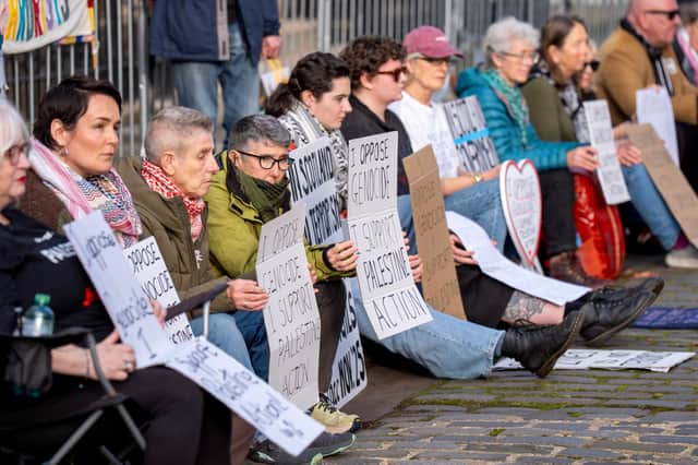 The protesters sit outside the US consulate with their placards. Picture: Jane Barlow/PA.