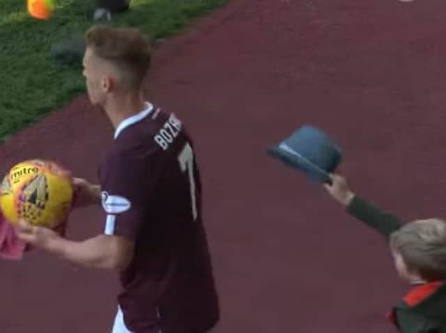 The young lad tries to place the hat on Oli Bozanic's head as the Hearts midfielder goes to take a throw in.