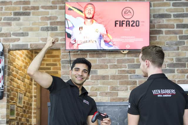 Harry Razvi (left) seen here playing FIFA at the Veen Barbers shop in Musselburgh. Veen Barbers are inviting customers to come in and try and beat Harry on the FIFA 20 computer game .Picture: Ian Rutherford