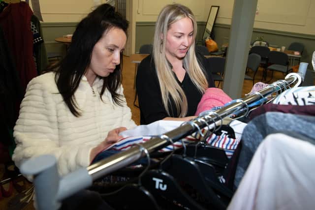 Natalie browses the clothes rack with volunteer Rachel.