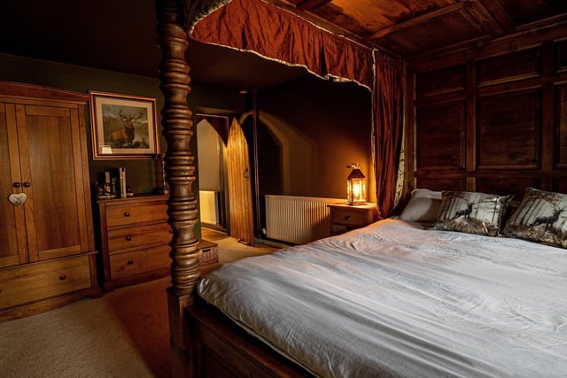 The roundhouse cottage features six handmade wooden four poster single beds each of which have red curtains and bed spreads and golden roman numerals etched on the front of their frames. (Credit: Charlotte Graham)