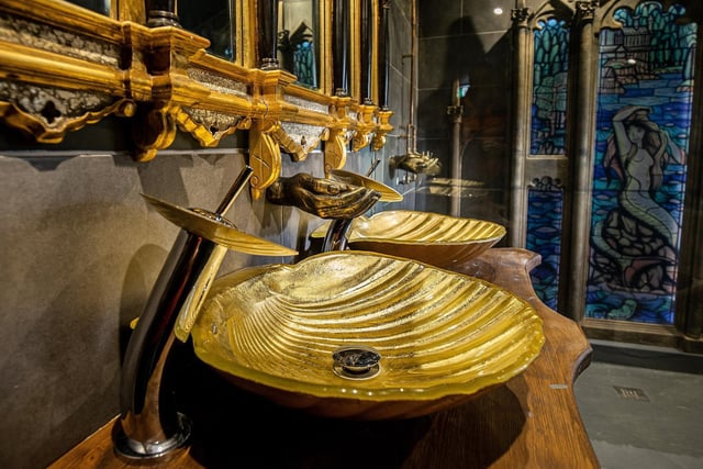 The opulent bathroom features ornate Gothic style mirrors and golden hand basins in the shape of giant shells. (Credit: Charlotte Graham)