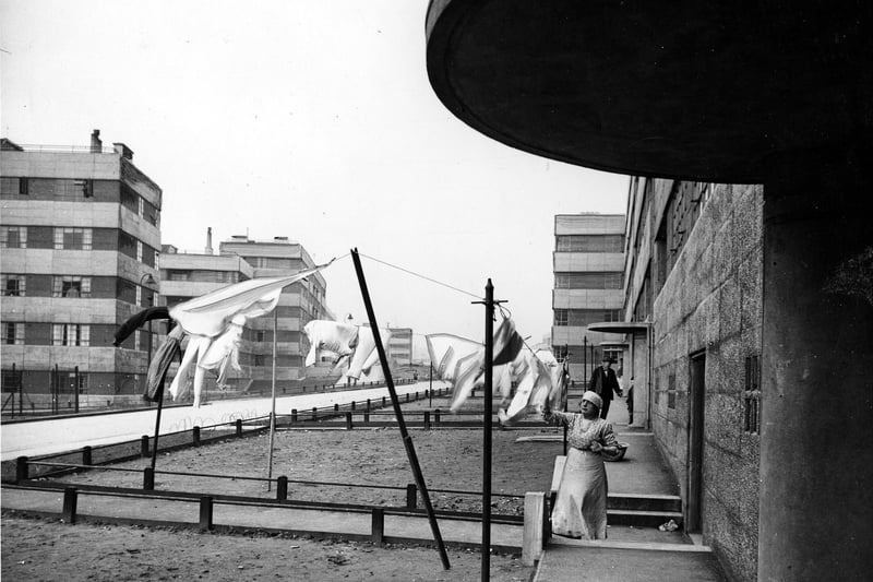 1939 and a woman stands outside Lupton House hanging out washing on lines which are strung across small, as yet undeveloped garden plots.