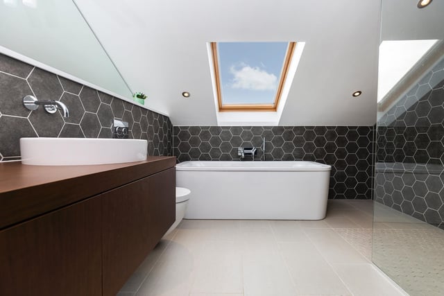 Clean lines in this mirrored bathroom with its deep bath tub and basin with vanity unit.