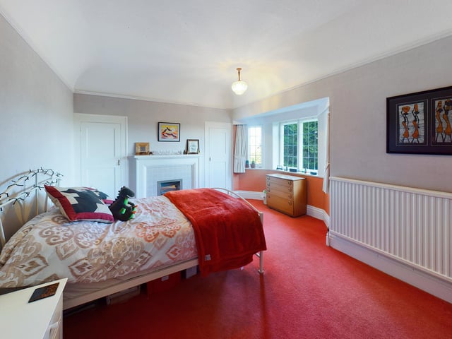 This bedroom has a fireplace and bay window, afgain with plenty of floor space.