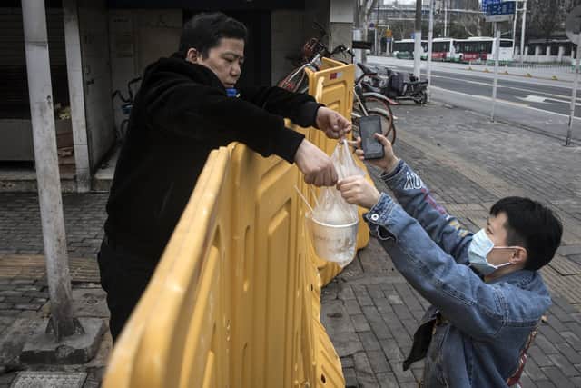 A man sells breakfast to nurses behind a makeshift barricade built to control entry and exit to a residential compound in Wuhan, China (Picture: AFP via Getty Images)
