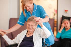 A care worker encourages a Jenny's Well care home resident to stretch her arms. Photo: Royal Blind
