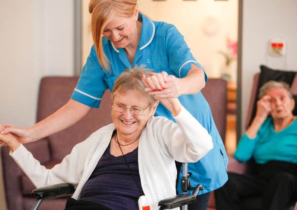 A care worker encourages a Jenny's Well care home resident to stretch her arms. Photo: Royal Blind