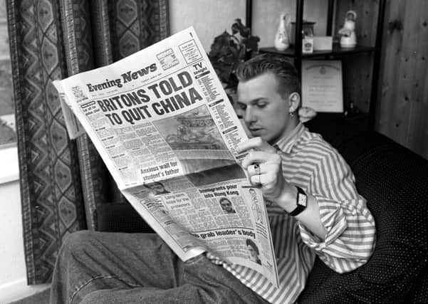 A reader browses through a broadsheet Evening News in 1989. Papers provide continuity and community (Picture: Norman Wilson)