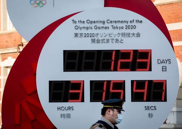 A police officer wearing a face maskwalks past the Olympic countdown clock in Tokyo  (Picture: Behrouz MehriI/AFP)