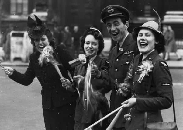 An RAF officer, two members of the Women's Royal Airforce and a civilian celebrate the news of victory in London's Whitehall (Picture: Fox Photos/Getty Images)