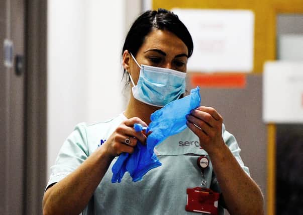 A nurse puts on her PPE (Picture: Michael Gillen)