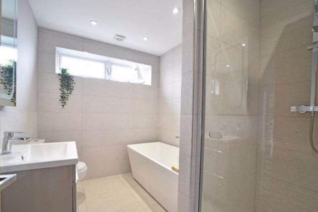 The family bathroom has a twin ended bath with a wall mounted mixer tap, vanity washbasin and ceramic tiled shower with a glazed pivot door, a heated towel rail and mounted mirror with lighting.