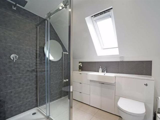 The en suite bathroom connecting to the master bedroom has a vanity wash basin with cupboards and a ceramic tiled shower cubicle with a sliding door.