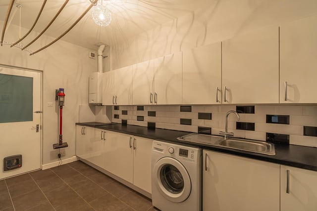 The large utility room with clothes pulley, base and wall mounted units and integrated washing machine.