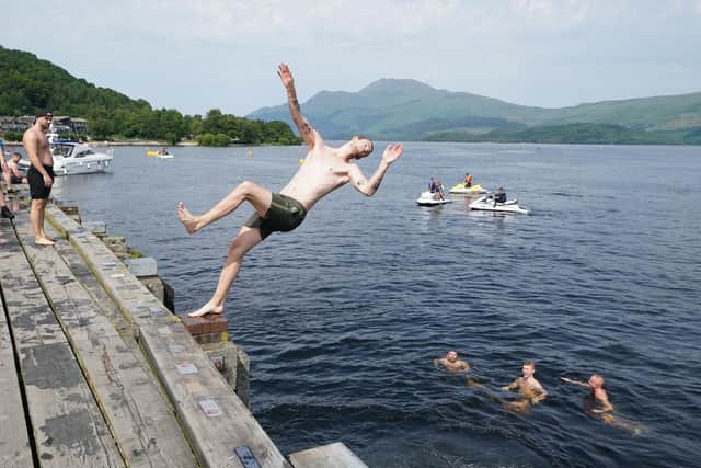 Swimmers jumping into Loch Lomond from a pier at Luss on Tuesday. Picture: Andrew Milligan/PA Wire
