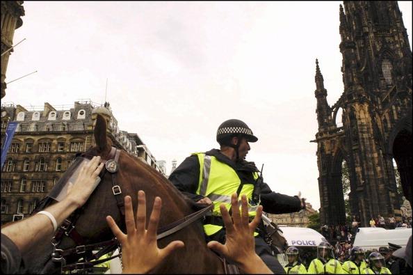 A police horse on Princes Street surrounded by protesters.