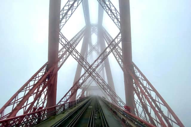 The image shows the famous red steel beams of the cantilever bridge criss-crossing each other above the empty train tracks below, while the world around them is masked by thick fog. (Taylor Bennie)