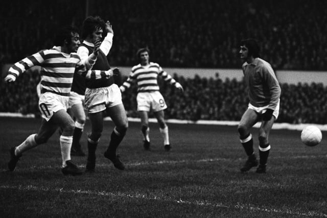Celtic's Lou Macari (left) is held off by Erich Schaedler as Hibs goalkeeper Jim Herriot looks on