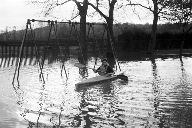 A canoeist paddles through Roseburn Park swing park when the Water of Leith overflowed after flooding in Edinburgh, November 1984.