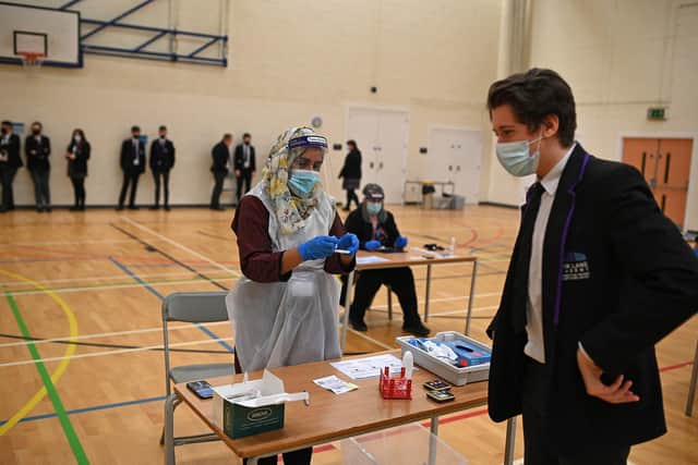 A member of staff wearing PPE processes a student's Innova lateral flow Covid-19 test, in the Sports Hall at Park Lane Academy in Halifax, northwest England.