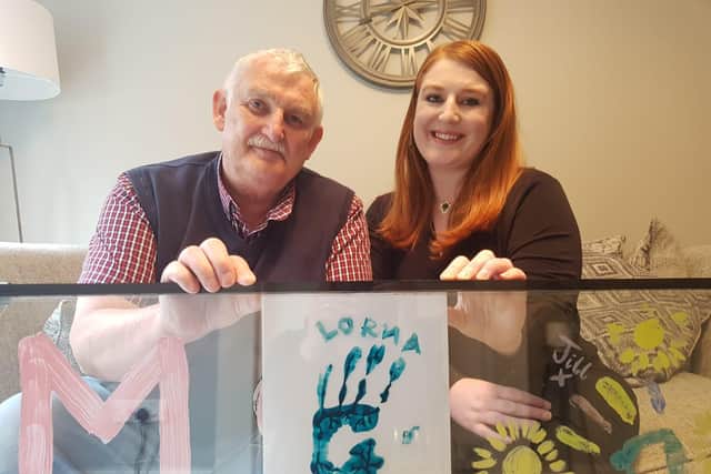 Lorna’s daughter Amy and husband Ashley with their artwork featuring Lorna’s handprint. (A piece of paper has been placed behind the handprint to make it stand out for photo purposes.)