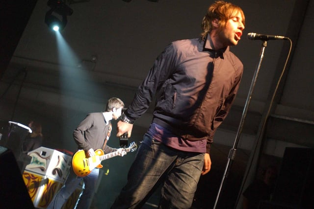 Oasis frontman Liam Gallagher at the microphone, on stage at the Corn Exchange in Edinburgh, with brother Noel on guitar in the background, in September 2002.