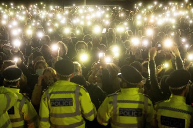 People in the crowd turn on their phone torches at the vigil in Clapham Common that turned ugly