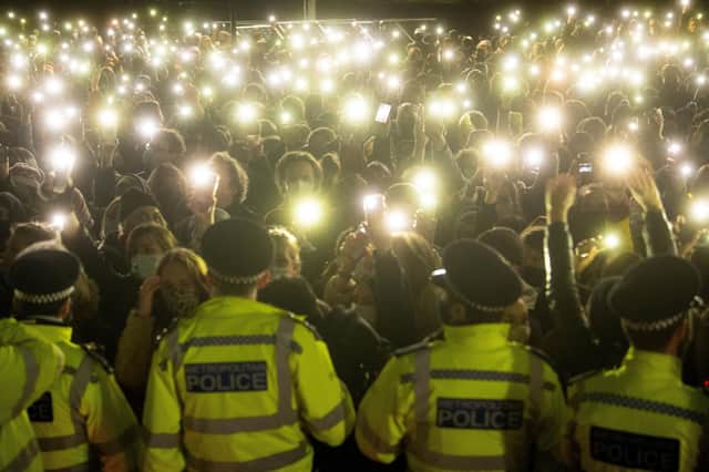 People in the crowd turn on their phone torches at the vigil in Clapham Common that turned ugly