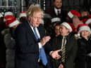 Boris Johnson applauds a group of young singers as he attends the switch-on of the Downing Street Christmas tree lights (Picture: Justin Tallis/AFP via Getty Images)