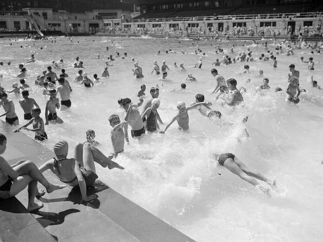 Holiday makers at Portobello Outdoor Swimming Pool having fun in the waves in July 1955.