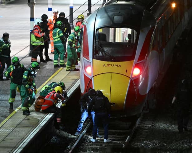 Police officers and members of the emergency services search the track beneath an LNER Azuma train at Huntingdon Station