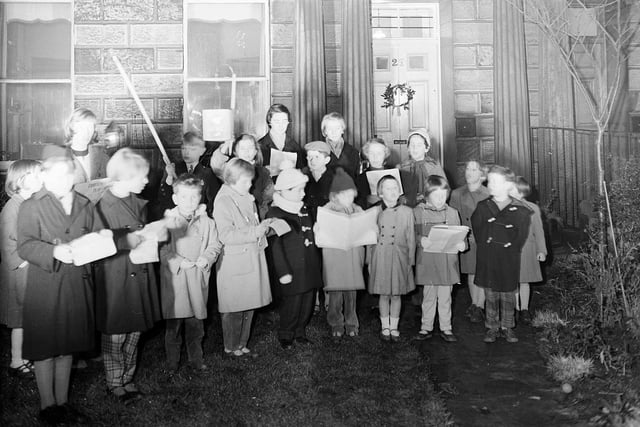 Children sing Christmas carols in front of the house at 29 Ann Street, Edinburgh for the Ann Street Society, in December, 1958.