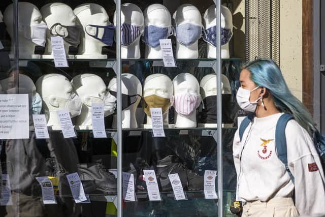 A woman wearing a protective face mask walks past a shop selling masks in Edinburgh city centre. Picture: PA