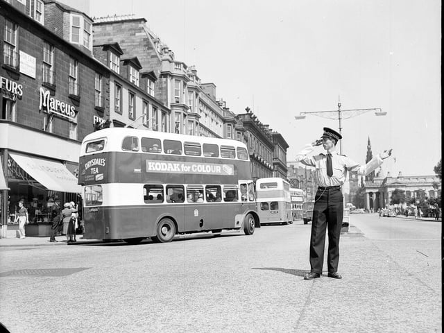 Policeman Ian Milne directs traffic in his shirt sleeves in Princes Street outside Marcus the Furrier during an Edinburgh heatwave in July 1962.